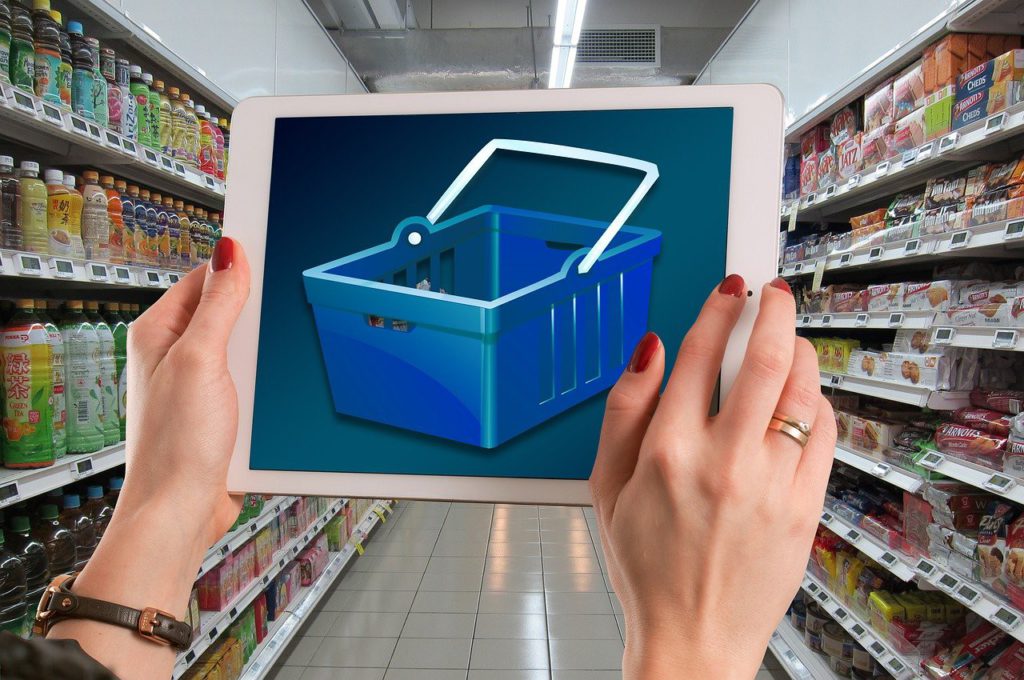 A women in a supermarket shows on her tablet an image of a supermarket basket