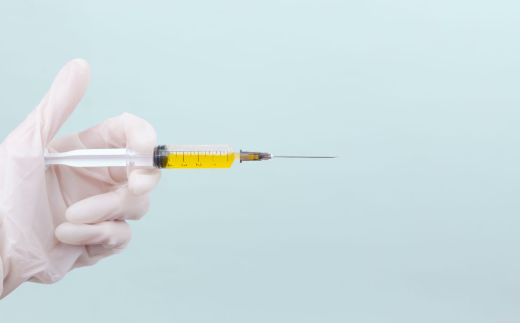 Medical syringe needle contains yellow liquid